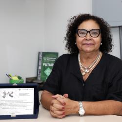 Mulher com cabelo escuro curto, óculos de grau em escritório.