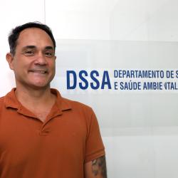 Homem Branco, cabelo curto, camisa na cor de tijolo em frente ao blindex do departamento.