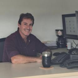 homem branco, camisa vinho, cabelo escuro curto, em escritório.