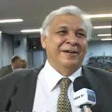 homem sorrindo, cabelo branco, de terno e gravata cinza.